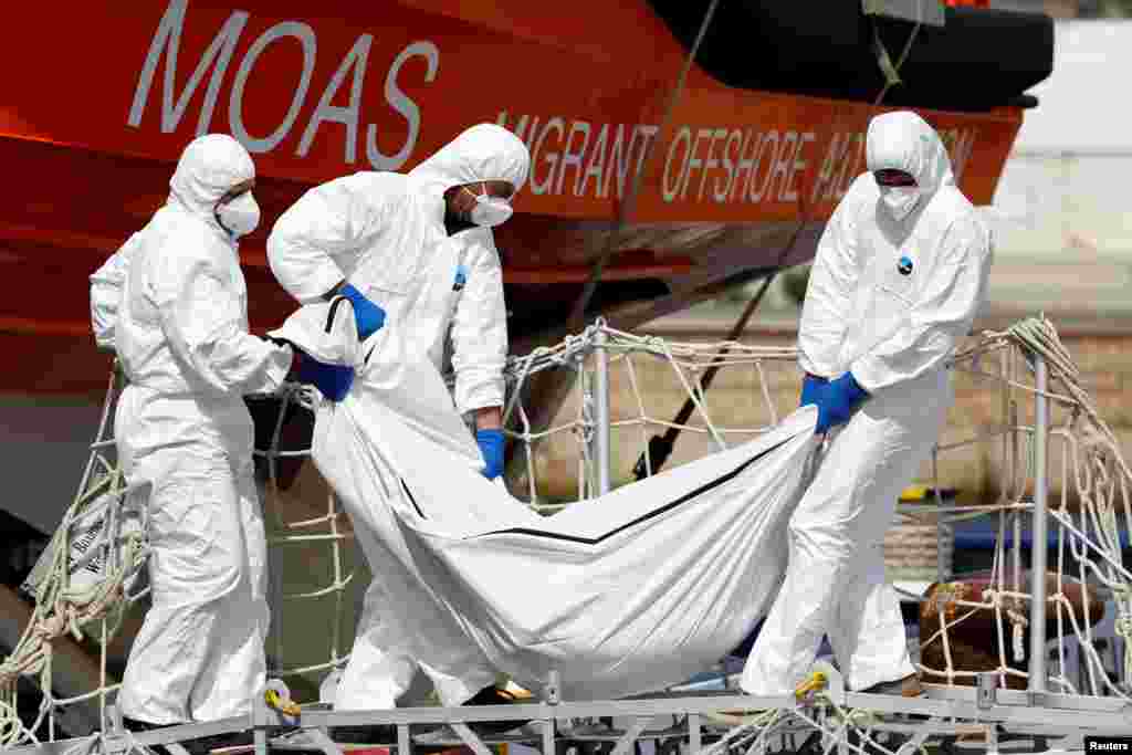 People carry the body of a dead migrant from the vessel Topaz Responder as they arrive in the Sicilian harbor of Augusta, Italy.