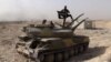 FILE - An Islamic State militant holds the group's flag as he stands on a tank captured from Syrian government forces, in the town of al-Qaryatayn southwest of Palmyra, central Syria. 