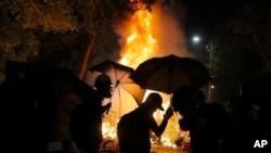 Students walk by a fire during a clash with police at the Chinese University in Hong Kong, Tuesday, Nov. 12, 2019. Police and protesters battled outside university campuses and several thousand demonstrators blocked roads as they took over a central…