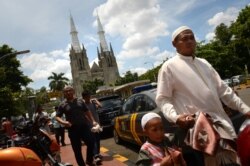 Umat Muslim hendak menunaikan sholat di masjid Istiqlal yang terletak di seberang Gereja Katedral, Jakarta (nampak di latar belakang), 29 Maret 2013. (Foto: dok).