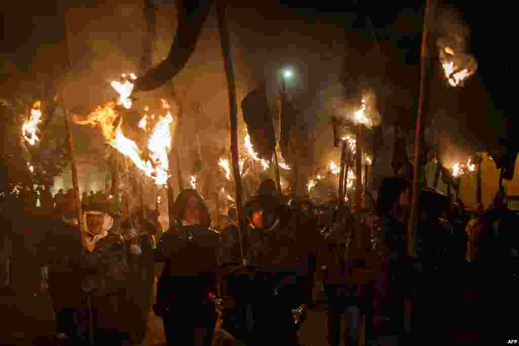 "Mayorganos" (Mayorga locals) carry hanging wineskins in flames that serve as torches take part in the "Vitor's Civic Procession" in Mayorga, near Valladolid, on Sept. 27, 2016.