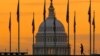 FILE - An early morning pedestrian is silhouetted against sunrise as he walks through the U.S. Flags on the National Mall and past the US Capitol Building in Washington Monday, Nov. 7, 2022, 