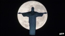 The silhouette of the statue of Christ the Redeemer atop Corcovado hill stands out against the full moon in Rio de Janeiro, Brazil, on July 19, 2016.