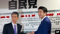 Perdana Menteri Jepang, Shinzo Abe (kanan), pemimpin Partai Demokratik Liberal berfoto bersama Wakil Presiden Masahiko Komura sambil menandai nama-nama politisi yang terpilih dalam pemilihan majelis rendah parlemen di markas Partai LDP di Tokyo, Jepang, 22 Oktober 2017. 