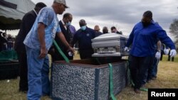 Sejumlah petugas tampak mengangkat peti mati yang berisi jenazah seorang warga yang meninggal akibat COVID-19 dalam upacara pemakaman di San Felipe, Texas, pada 26 Januari 2021. (Foto: Reuters/Callaghan O'Hare)