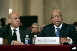 FILE - Sen. Cory Session, D-N.J. listens at left as Rep. John Lewis, D-Ga. testifies on Capitol Hill in Washington, Jan. 11, 2017, at the second day of a confirmation hearing for attorney general-designate, Sen. Jeff Sessions, R-Ala..