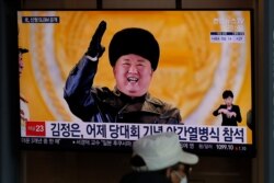 A man wearing a face mask sits in front of a TV screen showing North Korean leader Kim Jong Un, at the Seoul Railway Station in Seoul, South Korea, Friday, Jan. 15, 2021. The letters read "Kim Jong Un attended stage in Thursday night's parade…