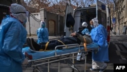 Medical staff in protective clothes are seen carrying a patient from an apartment suspected of having the virus in Wuhan, in Hubei province on January 30, 2020.
