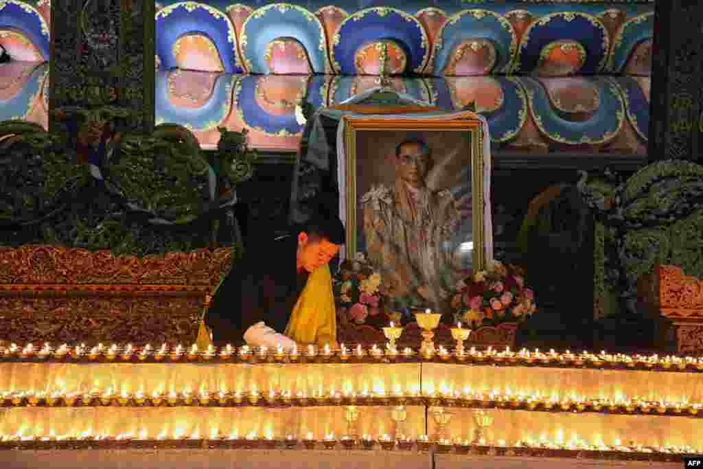 This photograph released by Bhutan's Royal Office for Media shows King Jigme Khesar lighting candles at the Kuenra of the Tashichhodzong in Thimpu next to a portrait of Thailand's King Bhumibol Adulyadej, who died in Bangkok.