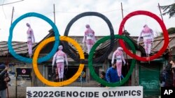FILE - Exile Tibetans use the Olympic Rings as a prop as they hold a street protest against the holding of 2022 Winter Olympics in Beijing in Dharmsala, India, Feb. 3, 2021. 