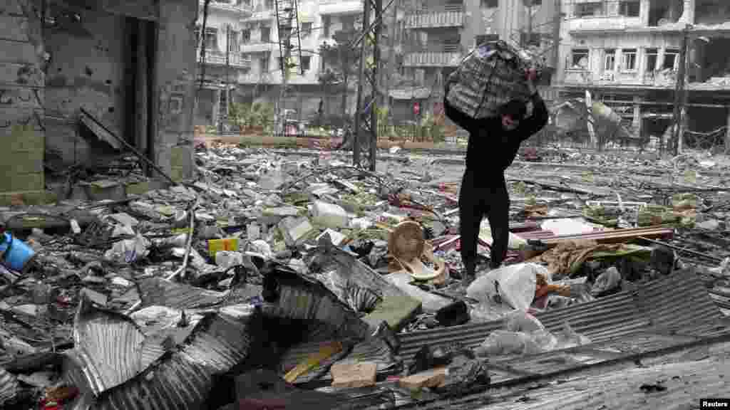 A man carries a bag amid damage and debris in the besieged area of Homs, Jan. 26, 2014.