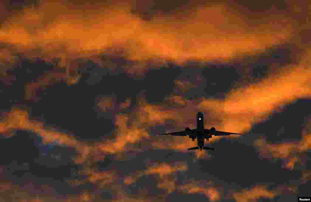 A passenger plane flies toward Heathrow airport at dawn in London, Britain