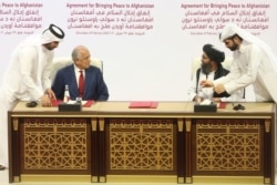FILE - In this Feb. 29, 2020, U.S. peace envoy Zalmay Khalilzad, left, and Mullah Abdul Ghani Baradar, the Taliban group's top political leader sign a peace agreement between Taliban and US officials in Doha, Qatar.