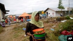 Seorang migran Rohingya di tempat penampungan sementara di Kuala Langsa, Aceh, membawa piring kotor yang digunakan setelah makan utuk dicuci (Foto: dok).