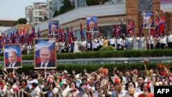 Луѓето ги поздравуваат севернокорејскиот лидер Ким Џонг Ун и рускиот претседател Владимир Путин за време на посетата на Путин, на плоштадот Ким Ил Сунг во Пјонгјанг, 19 јуни 2024 година. Фотографија: Спутник преку агенција Франс - прес.
