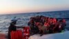 Seorang anggota kelompok LSM "Sea-Watch" memberikan jaket pelampung kepada para migran Afrika yang berdesakan menaiki kapal karet di lepas pantai Libya di Laut Tengah, 23 Juli 2022. 