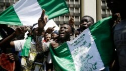 People hold banners as they demonstrate on the street to protest against police brutality, in Lagos, Nigeria, Tuesday Oct. 20, 2020. After 13 days of protests against police brutality, authorities have imposed a 24-hour curfew in Lagos, Nigeria's largest