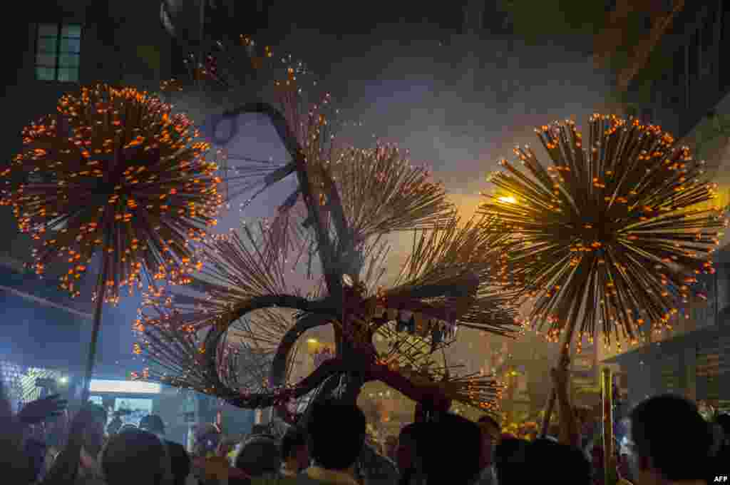 Members of the fire dragon dance team hold up the 'dragon' as it winds through the narrow streets and houses during the Tai Hang Fire Dragon Dance in Hong Kon.