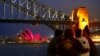 A group of people sit on a stone wall in front of the Sydney Opera House as it is illuminated in pink lights to mark the marriage equality bill being passed this week by the Australian parliament in Sydney, Australia, Dec. 8, 2017. 