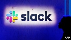 In this file photo taken on April 24, 2019, an attendee walks by the company’s logo during a Slack event on April 24, 2019, in San Francisco, California.