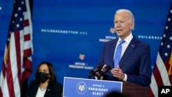 FILE - President-elect Joe Biden speaks as Vice President-elect Kamala Harris, left, listens during an event to introduce their future administration's nominees and appointees, at The Queen theater in Wilmington, Delaware, Dec. 1, 2020. 