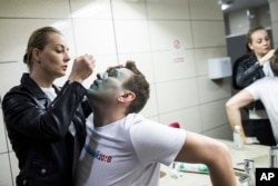 FILE - Yulia, wife of Russian opposition leader Alexei Navalny, treats him after unknown attackers doused him with green antiseptic outside a conference venue in Moscow, Russia, April 27, 2017.