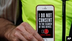 Seorang pria mengangkat iPhone miliknya untuk mendukung demo privasi di luar toko Apple di San Fransicso, Calif., 23 Feb 2016.