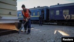 Seorang petugas kebersihan membersihkan area yang menjadi target serangan militer Rusia di sebuah stasiun kereta di Kherson, Ukraina, pada 27 Desember 2023. (Foto: Reuters/Oleksandr Ratushniak)