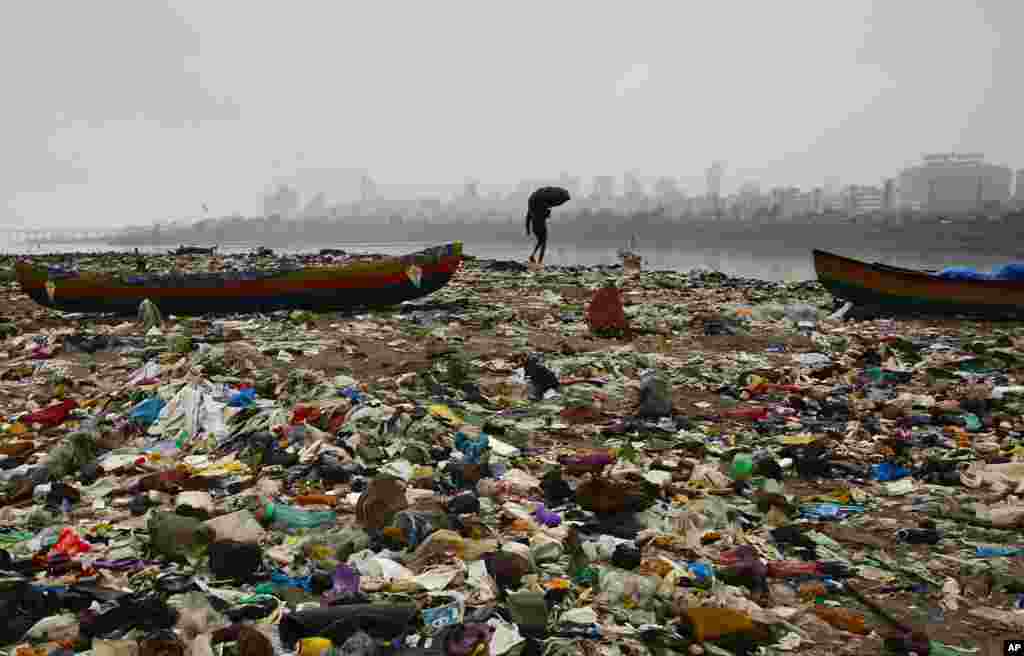 A fisherman walks on the shores of the Arabian Sea, littered with plastic bags and other garbage, in Mumbai, India.