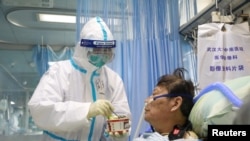 Seorang perawat dalam pakaian pelindung memberi makan seorang pasien yang tertular virus corona di Rumah Sakit Zhongnan, Wuhan, China. (Foto: Reuters)