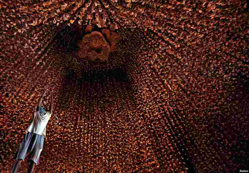 An artisan hangs decorative pieces at a pandal, or a temporary platform, for the upcoming Hindu festival of Durga Puja, in Kolkata, India.