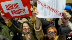 Ilustracija - dve žene drže transparente na protestu protiv izbornih neregularnosti koalicije "Srbija protiv nasilja" u decembru 2023. (AP Photo/Darko Vojinovic)