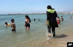 FILE - Nissrine Samali, 20, gets into the sea wearing traditional Islamic dress, in Marseille, southern France.