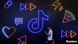 FILE - Seorang pria memegang telepon berjalan melewati tanda aplikasi TikTok milik perusahaan China ByteDance, yang dikenal secara lokal sebagai Douyin, di Pameran Produk Buatan Internasional di Hangzhou, provinsi Zhejiang, China, 18 Oktober 2019.