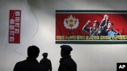 북한 평양326전선공장에 게시된 구호 앞으로 근무자들이 지나가고 있다. (자료사진)
