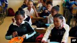 FILE - Students have a meal they received from a government sponsored feeding scheme at the Delta Primary School in Vosburg, South Africa, Nov. 14, 2019. 