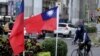 Seorang pengendara sepeda di samping dua bendera nasional Taiwan di Taipei. (Foto: AFP)