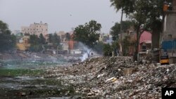 A homeless person burns garbage in the polluted river Cooum in Chennai in southern Indian state of Tamil Nadu, July 20, 2019.
