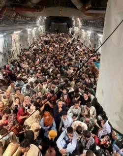 Afghan citizens pack inside a U.S. Air Force C-17 Globemaster III, as they are transported from Hamid Karzai International Airport in Afghanistan, Sunday, Aug. 15, 2021. The Taliban on Sunday swept into Kabul, the Afghan capital, after capturing most of