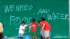 Children help to carry pails of drinking water as they walk past graffiti calling for help after Typhoon Haiyan devastated Tacloban city, central Philippines, Nov. 12, 2013.