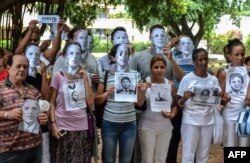 FILE - Cuban dissidents pose wearing masks depicting US President Barack Obama and holding pictures of imprisoned dissidents as they protest against the reopening of the US embassy in the island, Aug. 9, 2015.
