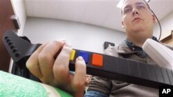 In this March 2016 photo provided by Ohio State University, Ian Burkhart plays a guitar video game as part of a study with neural bypass technology at The Ohio State University Wexner Medical Center in Columbus. A computer chip in Burkhart's brain reads h