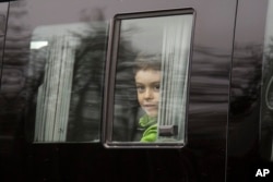 A boy looks through a bus window alleged to be carrying Russian diplomats and their family members who were ordered to leave the US, as they depart from Vnukovo 2 government airport, outside Moscow, Russia, April 1, 2018.
