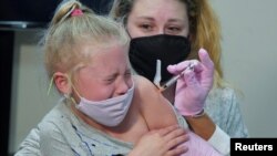Emma Ingle, 7 tahun, duduk di pangkuan ibunya Kim Obert, menerima dosis pertama vaksin virus corona Pfizer-BioNTech di Storrs, Connecticut, AS, 3 November 2021. (Foto: Reuters)