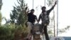 Members of the Free Syrian Army celebrate as they place their feet on a sculpture of late Syrian President Hafez al-Assad, father of Syrian President Bashar al-Assad, at the Brigade 52 military base in Daraa, Syria, June 9, 2015.