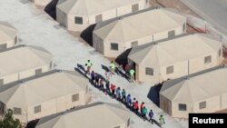 FILE - Immigrant children, many of whom were separated from their parents under a zero-tolerance policy by the Trump administration, are housed in tents next to the Mexican border in Tornillo, Texas, June 18, 2018.