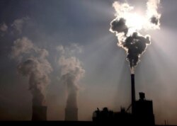 FILE - A coal-burning power plant can be seen behind a factory in China's Inner Mongolia Autonomous Region, October 31, 2010.