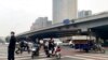 People ride scooters at an intersection near a bridge where social media videos earlier appeared to show smoke and protest banners in Beijing, Oct. 13, 2022. 