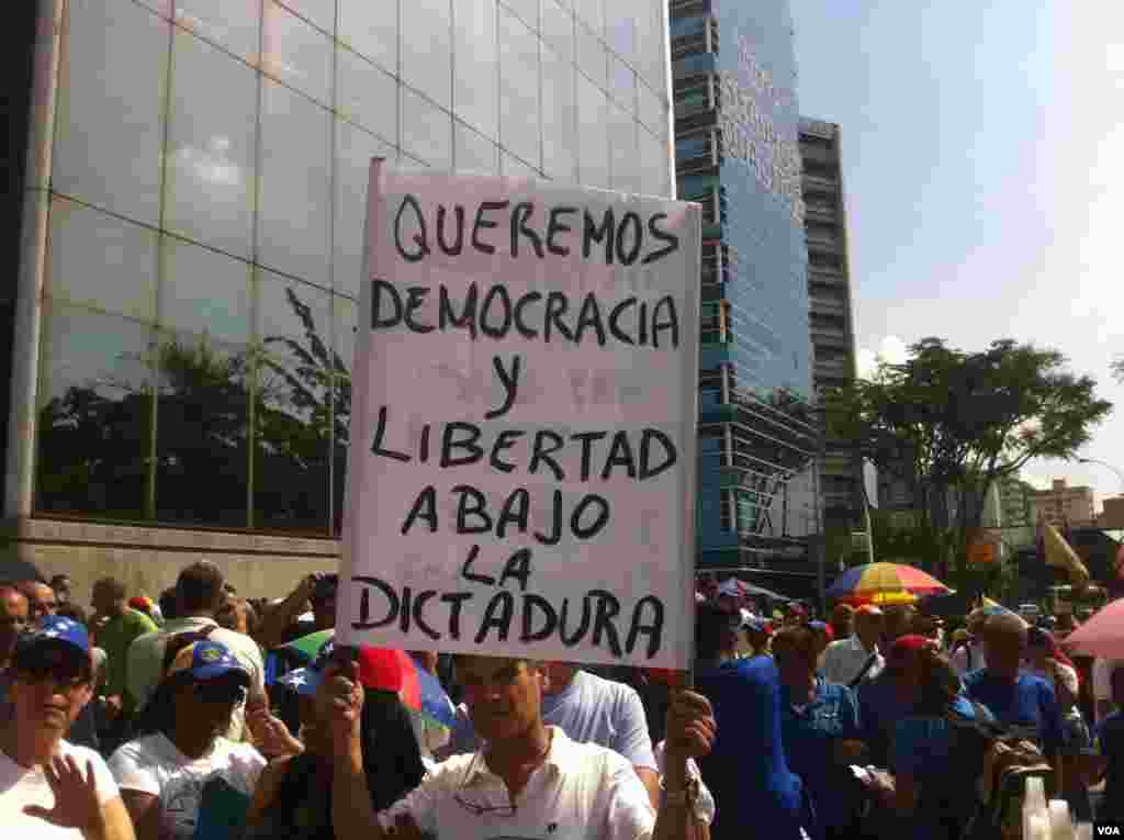 Opposition supporters march in Caracas against Venezuela's President Nicolas Maduro. Sign reads: "We want democracy and freedom - down with dictatorship." (A. Algarra/VOA)