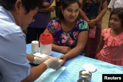 FILE - Seorang petugas kesehatan masyarakat mengambil sampel darah dari seorang perempuan untuk diuji malaria di distrik Bo Rai, provinsi Trat, Thailand.